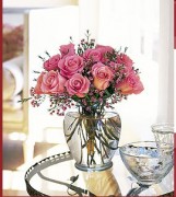 Twelve roses with waxflower in a classic glass vase.